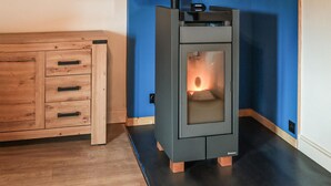 A modern kitchen with a built-in wood-burning stove, a wooden cabinet with drawers, and a blue accent wall.