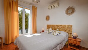 A bedroom with a large bed, two bedside tables, a window with curtains, an air conditioner, and a decorative sunburst mirror on the wall. - 3 bedroom awesome home in Casalabriva (Casalabriva)