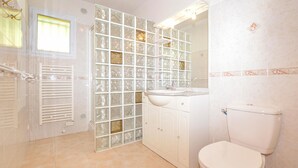 A bathroom with a toilet, sink, and glass block wall. - 3 bedroom awesome home in Casalabriva (Casalabriva)