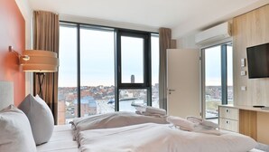 A hotel room with a large bed, a TV, and a view of the city through large windows. - Ohlerich storage app. 44 - Ohlerich Speicher App. 44 (Wismar)