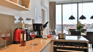 A modern kitchen with a view of the city, a red kettle, wine glasses, and a coffee maker. - Ohlerich storage app. 44 - Ohlerich Speicher App. 44 (Wismar)