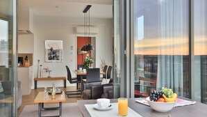 A modern hotel room with a dining area, a balcony with a view, and breakfast items on the table. - Ohlerich storage app. 44 - Ohlerich Speicher App. 44 (Wismar)
