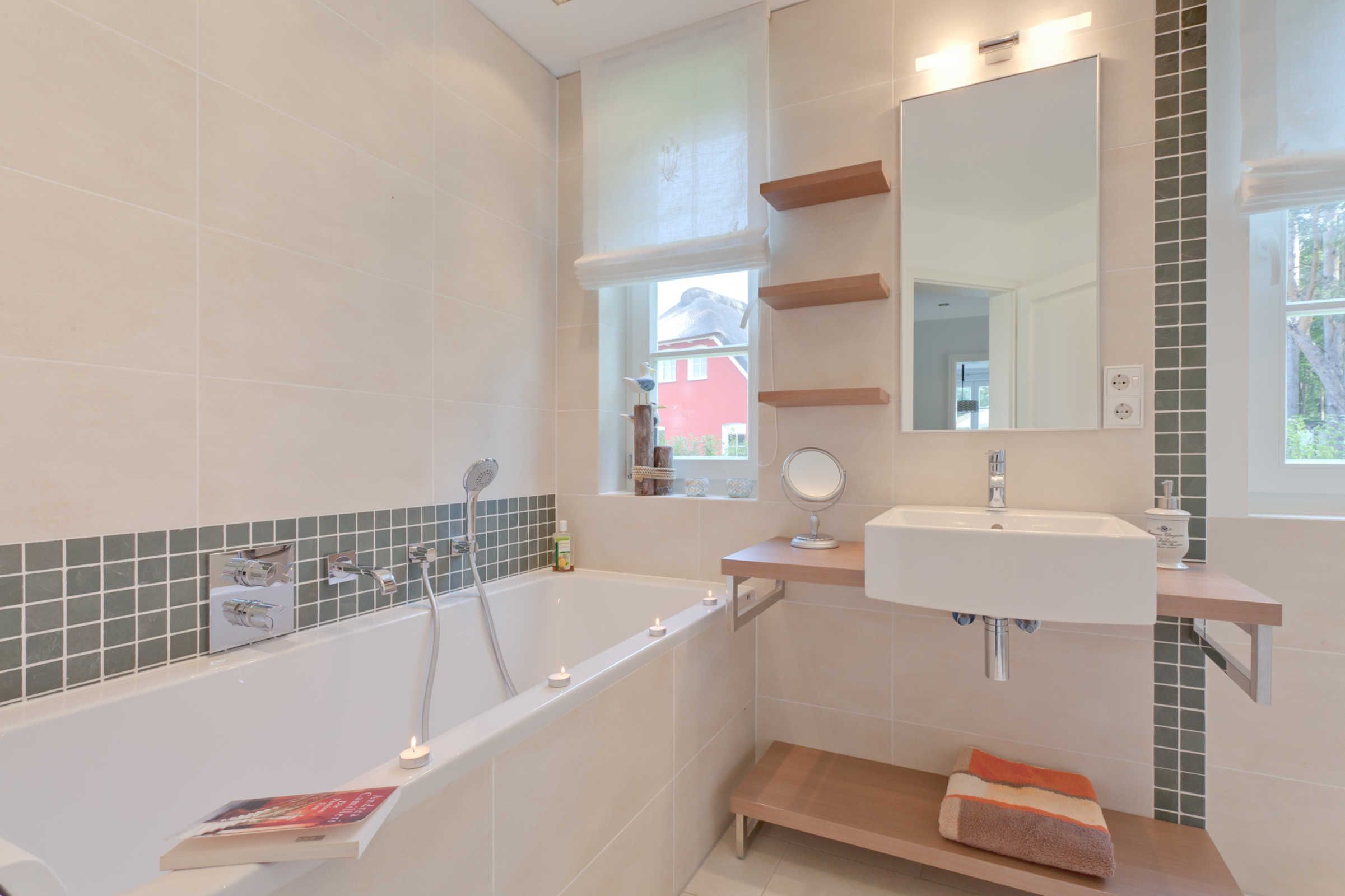A modern bathroom with a bathtub, a sink, and a mirror. There are shelves above the sink and a window above the bathtub.