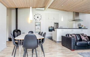 A modern kitchen with white cabinets, a central island, and a dining area with a wooden table and chairs. - Gorgeous home in Løkken with kitchen (Løkken)