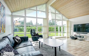 A spacious living room with a leather sofa, a round coffee table, and a large TV. - Gorgeous home in Løkken with kitchen (Løkken)