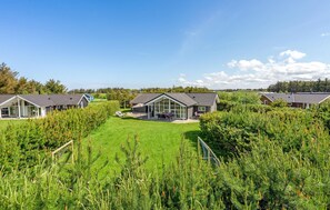 Een woonwijk met meerdere huizen, elk met een eigen architectuur, puntige daken en grote ramen.