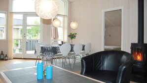 Una sala de estar moderna con chimenea, un comedor con sillas y un ventanal grande.