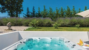 Een jacuzzi met vrij uitzicht op de omliggende tuin en bomen.