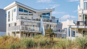 Een modern meerlaags woongebouw met balkons, grote ramen en een plat dak.