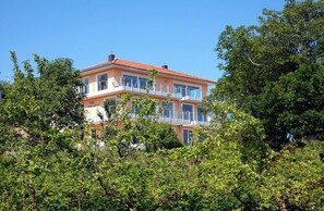 Un edificio a più piani con balconi, immerso nel verde.