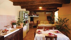 Une cuisine chaleureuse avec un coin repas, un plafond en bois et une cheminée.