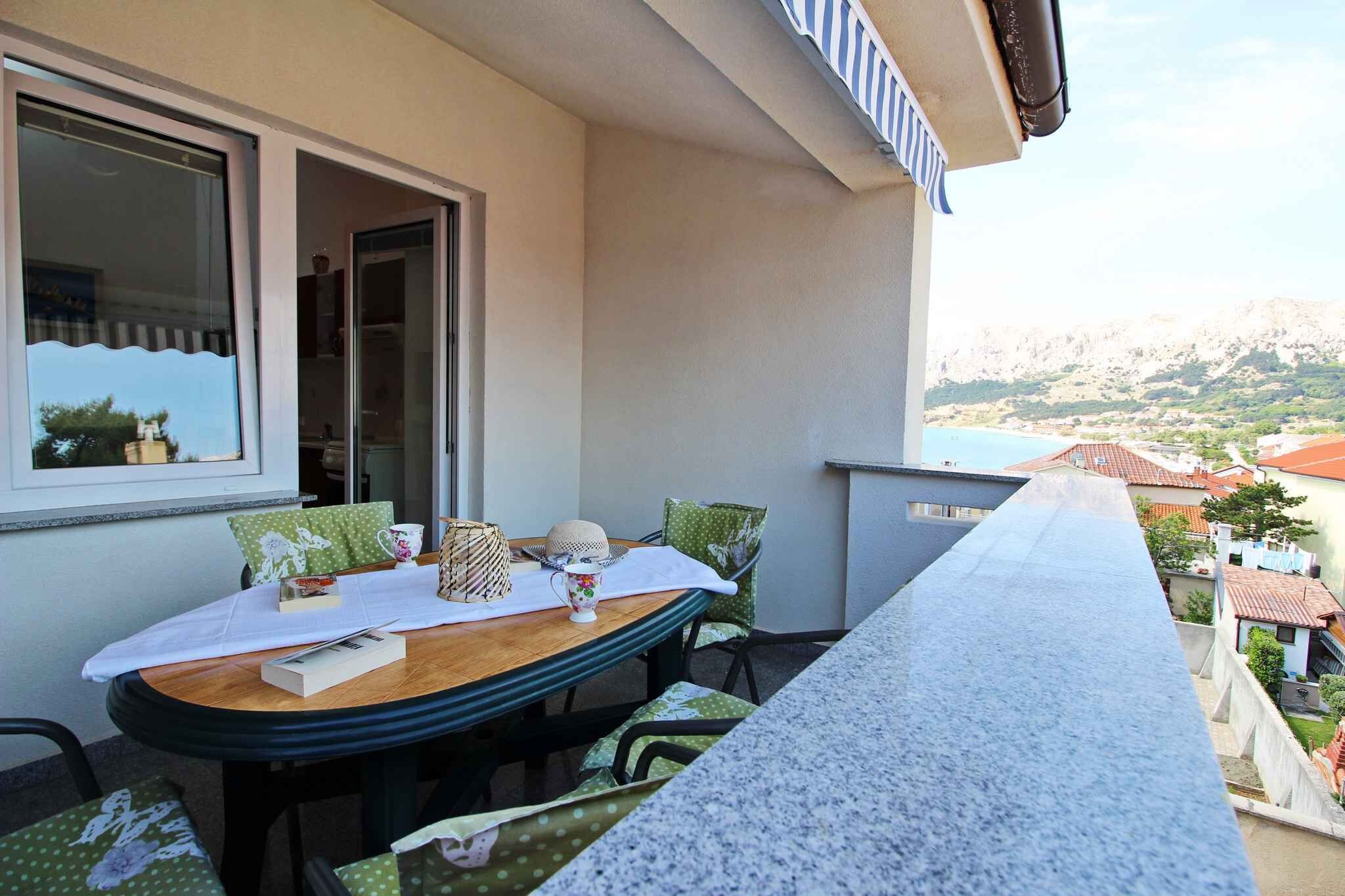 Un balcon avec une table dressée pour deux personnes, offrant une vue sur un paysage côtier.