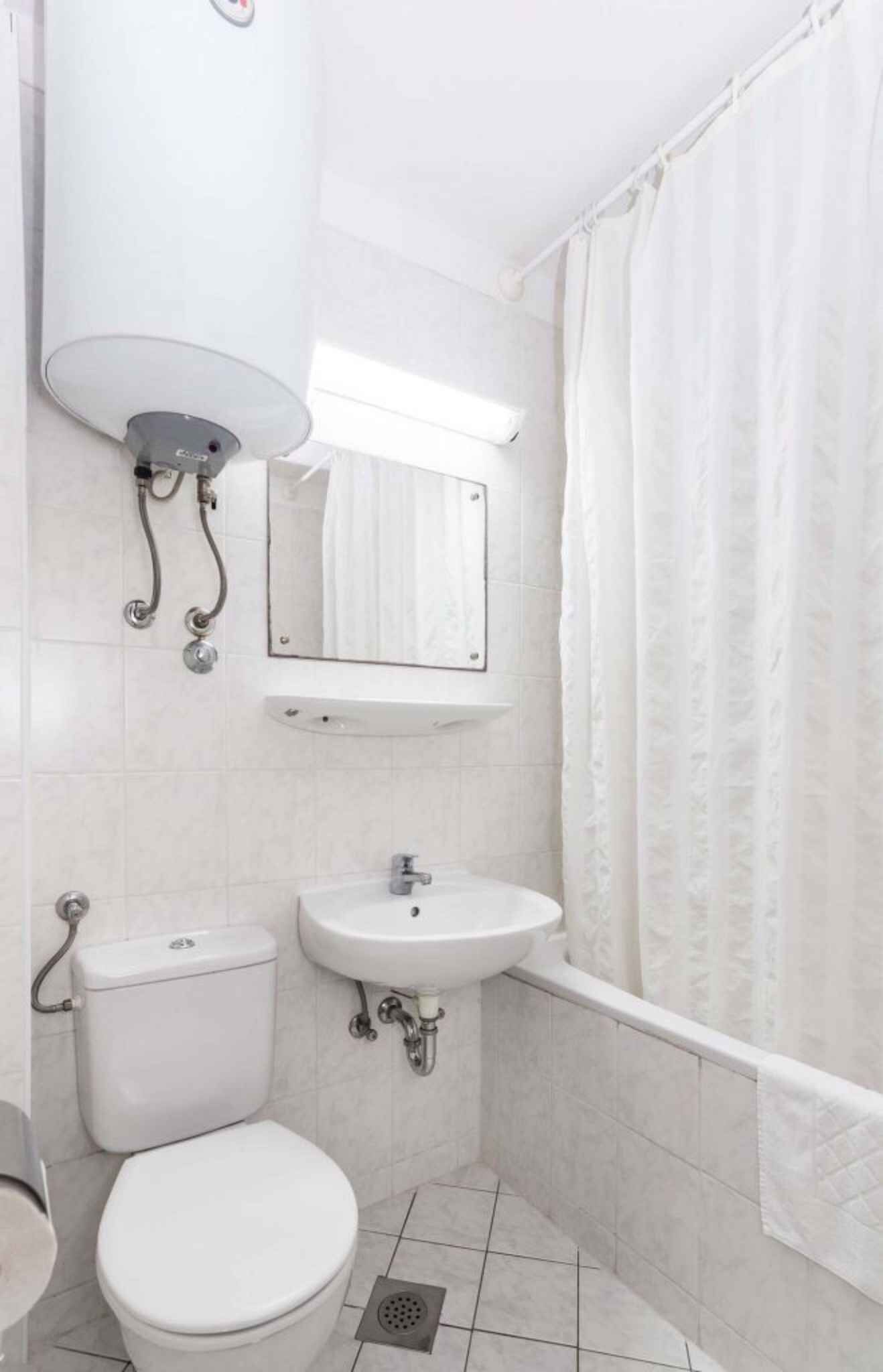 A small, clean bathroom with a toilet, sink, and shower.