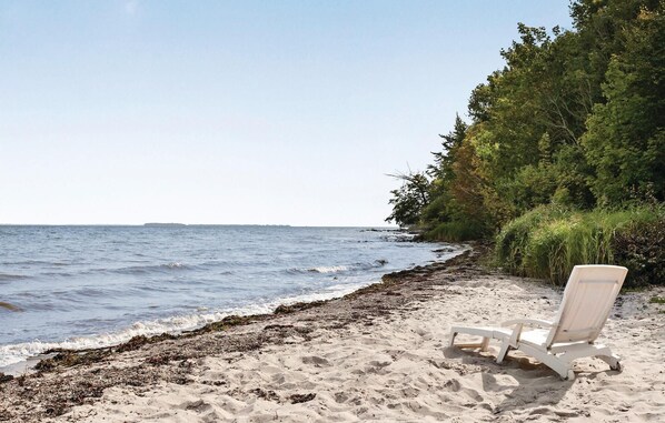 Une plage avec un fauteuil de plage blanc et une côte rocheuse.