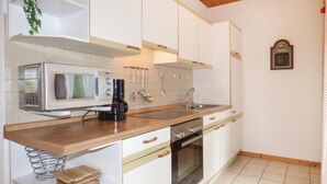 A compact kitchen with white cabinets, a microwave, a coffee maker, a sink, and a small oven.