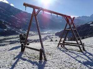A wooden swing set on a snowy mountain with a view of a valley and mountains in the background. - Vacation apartment for 7 people - Alpenjuwel (Laimach)