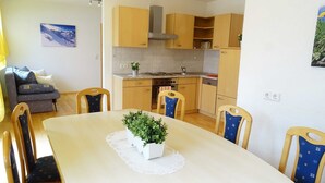 Une cuisine moderne avec des meubles en bois, une table à manger avec des chaises et une petite plante en pot posée sur la table.