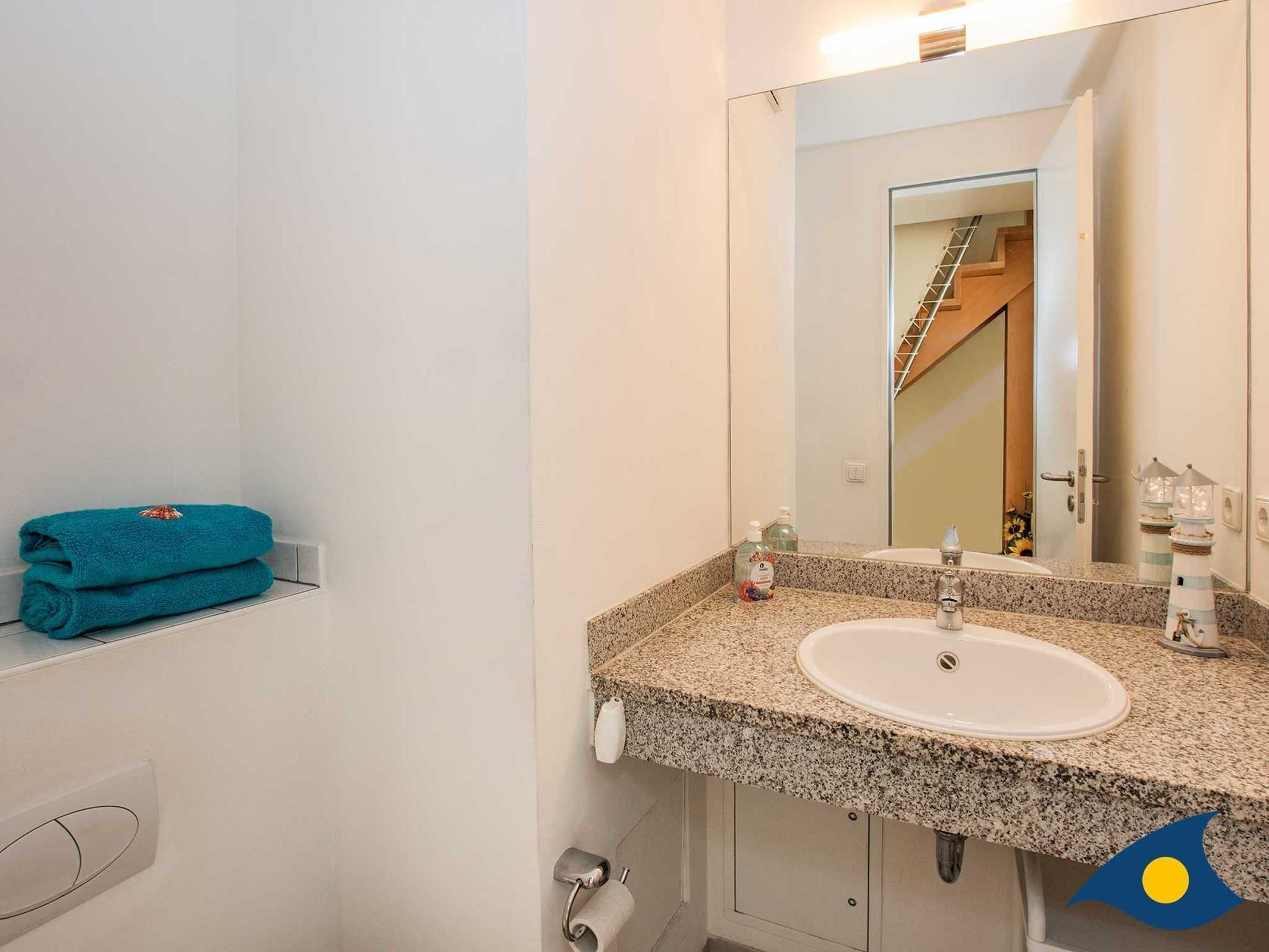 Un bagno con lavabo in granito, uno specchio, un porta asciugamani e un porta carta igienica.