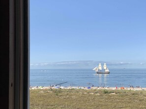 Ein Strand mit einem Segelboot, Zelten und Menschen.