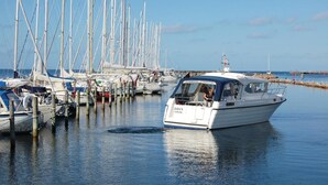 A marina with multiple sailboats docked, a motorboat in the foreground, and a rocky breakwater in the background. - Awesome home in Karrebæksminde with sauna (Karrebæksminde)