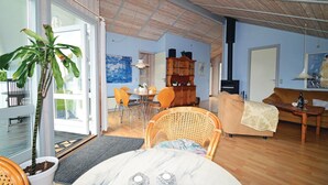 A spacious living room with a large window, a dining area, a sofa, and a fireplace. - Awesome home in Karrebæksminde with sauna (Karrebæksminde)