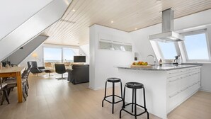 Eine moderne Küche mit einer großen Kochinsel, Barhocker und einem Essbereich mit Ausblick.