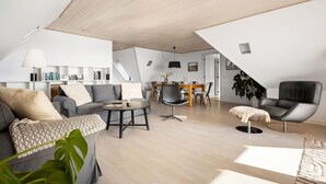 Ein geräumiges Loft mit hohen Decken, einem Essbereich, einer Couch und einem Sessel.