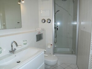 Une salle de bain équipée d’un lavabo, de toilettes et d’une douche à parois de verre.