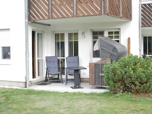 Een terras met twee stoelen en een tafel, een houten terras en een kleine boom.