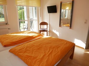 Une chambre avec deux lits, une télévision, une chaise et une fenêtre.