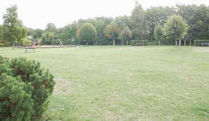Un espace vert avec des aires de jeux, des bancs et des arbres.