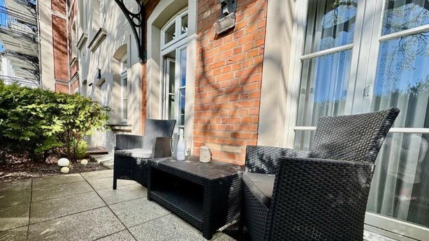 A patio with wicker furniture, a small table, and a potted plant. - (179) 2-room apartment - Apartment house Waldhaus (Kühlungsborn)