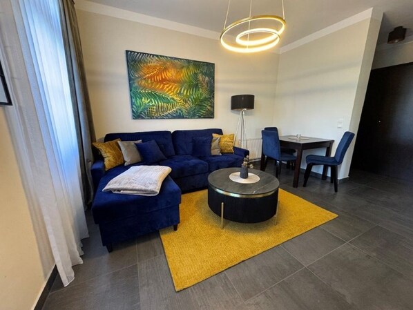 Una sala de estar moderna con un sofá azul, una mesa de centro redonda y una alfombra amarilla.