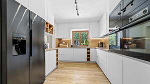 Een moderne keuken met witte kasten, een roestvrijstalen koelkast en een inbouwoven.