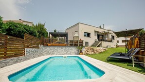 A modern house with a swimming pool, a patio with lounge chairs, and a stone wall. - Pet friendly home in Santa Susanna (Santa Susanna)