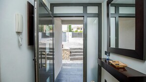 A hallway with a glass door leading to an outdoor area, a wooden bench, and a small decorative item on the wall. - Pet friendly home in Santa Susanna (Santa Susanna)