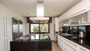 A modern kitchen with a central island, stainless steel appliances, and a large window providing a view of trees. - Pet friendly home in Santa Susanna (Santa Susanna)