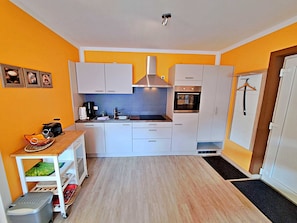 Una cocina compacta con armarios blancos, horno empotrado y cafetera.