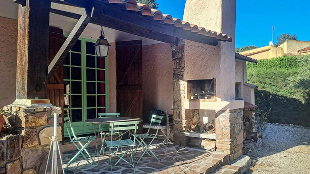 Une terrasse en pierre avec une table et des chaises, une cheminée en pierre et une vue sur le paysage environnant.