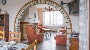 A cozy living room with a stone fireplace, leather sofas, and a dining area with a table set for two. - Cozy home in Villers-S/s-Foucarmont (Villers-S/s-Foucarmont)