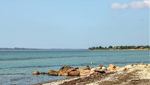 En strand vid kusten med stora stenar och fri utsikt över havet.