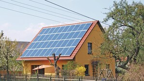 A house with a sloped roof, solar panels, a wooden fence, and a tree in the yard. - 4 bedroom awesome home in Woldegk (Woldegk)