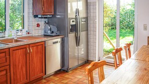 A kitchen with wooden cabinets, a stainless steel refrigerator, a dishwasher, and a dining area with a wooden table and chairs. - 4 bedroom awesome home in Woldegk (Woldegk)