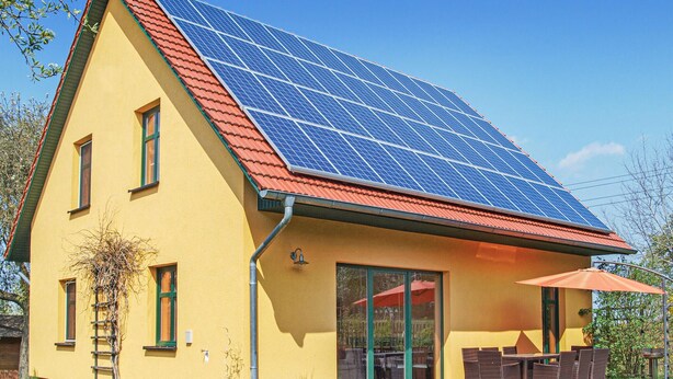 A yellow house with a red roof and a solar panel array. - 4 bedroom awesome home in Woldegk (Woldegk)