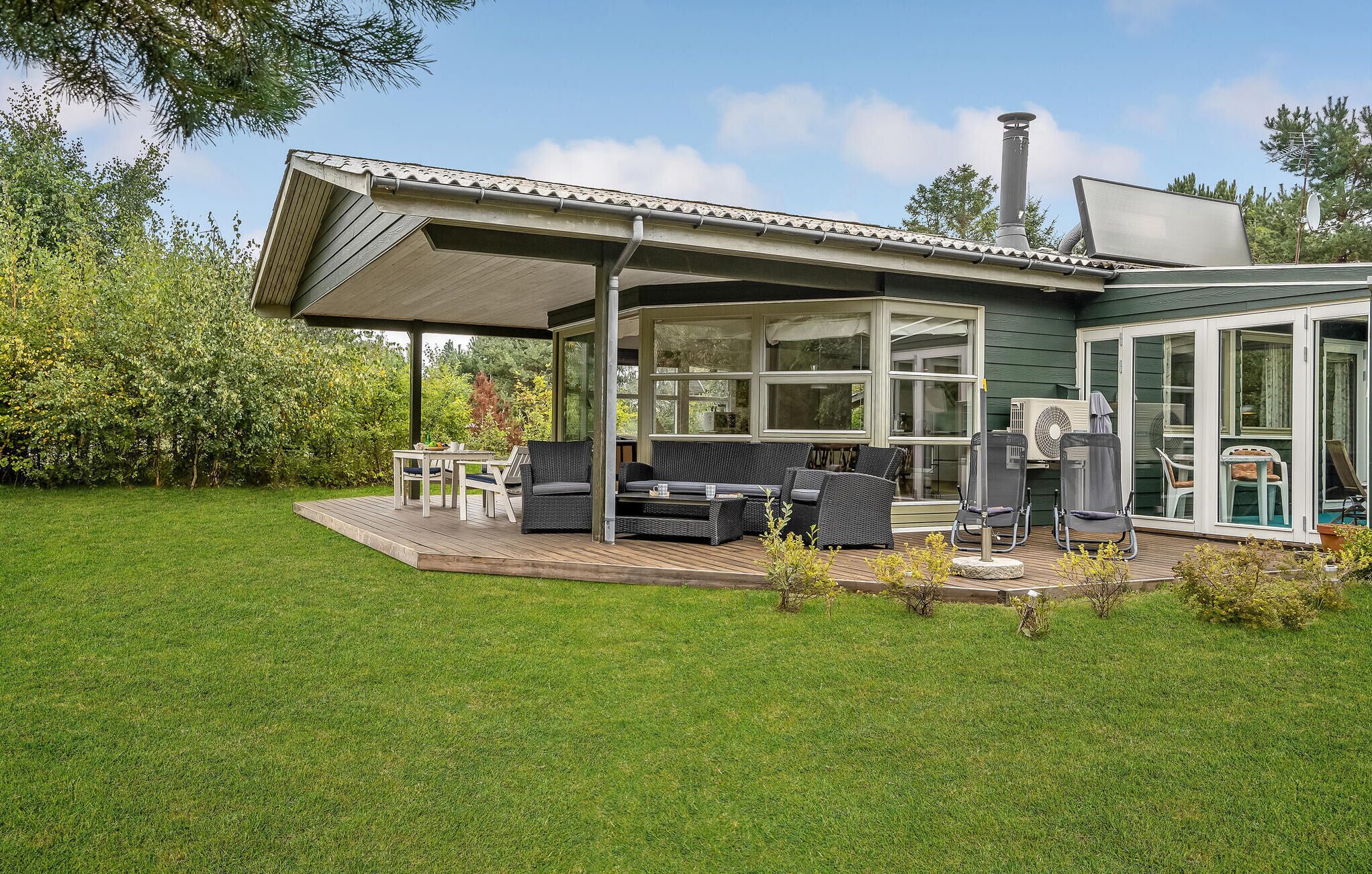 A modern house with a covered patio, outdoor seating, and a chimney.