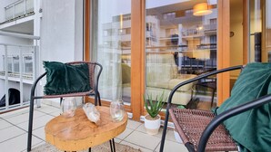 Een balkon met rieten stoelen, een houten tafel en een bloempot.