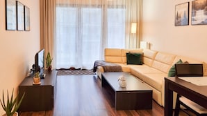 Een moderne woonkamer met een bank, salontafel en een bureau met een computer.
