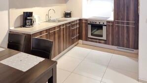 Een moderne keuken met houten kastjes, een roestvrijstalen oven en een koffiezetapparaat.