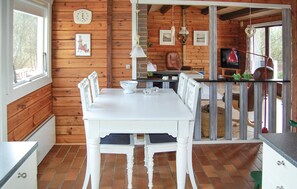 A wooden cabin interior with a dining table and chairs, a kitchen area, and a view through a glass door. - Amazing home in Rømø with kitchen (Rømø)