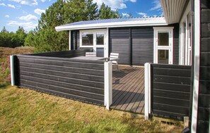 Una casa moderna con un porche cubierto, una puerta con paneles de vidrio y una pequeña terraza.